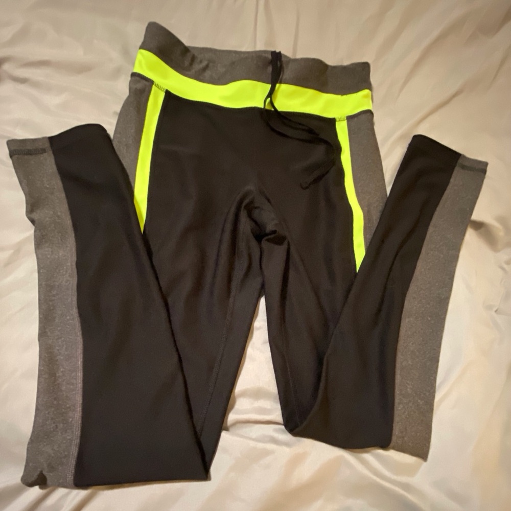 Xersion fitted leggings in black with neon yellow and gray details.